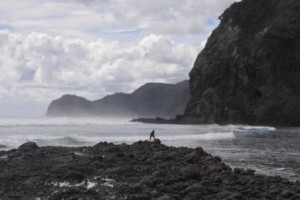 Late surfer at Piha with Lion Rock