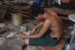 Lacquor Works. Youth with mobile phone tucked into his longyi